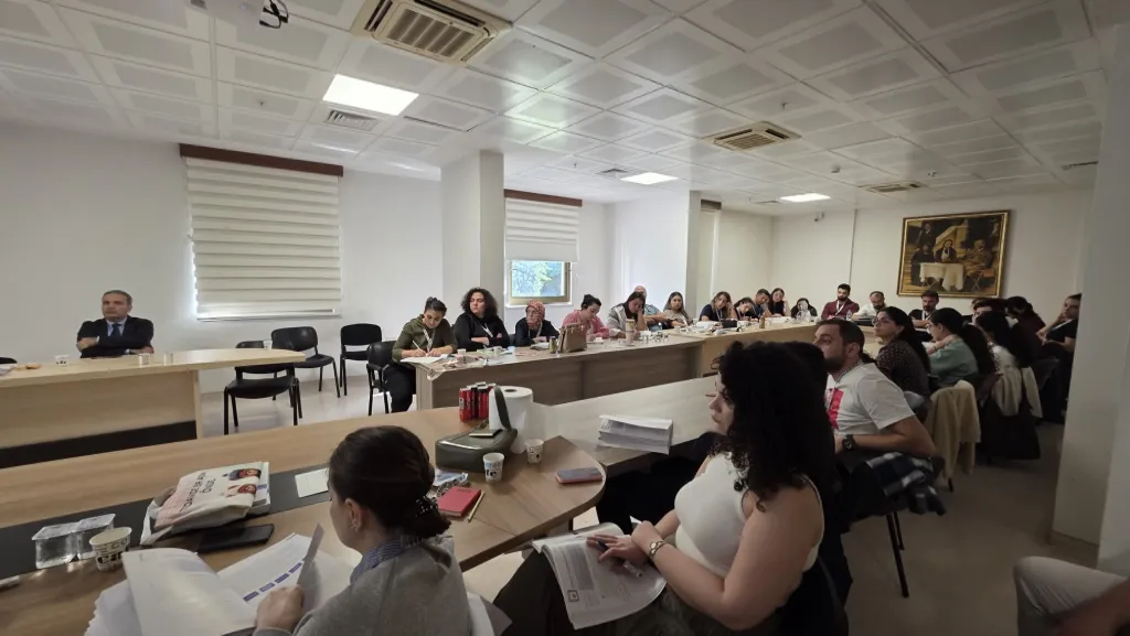 Toplantı salonunda masaların çevresinde oturan ÇİYAD Kursu katılımcıları
