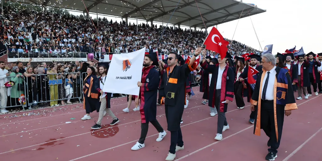 Mersin Üniversitesi genel mezuniyet töreninde, Üniversite Stadyumu'nda Tıp Fakültesi bayrağıyla yürüyen mezunlarımız ve öğretim üyelerimiz